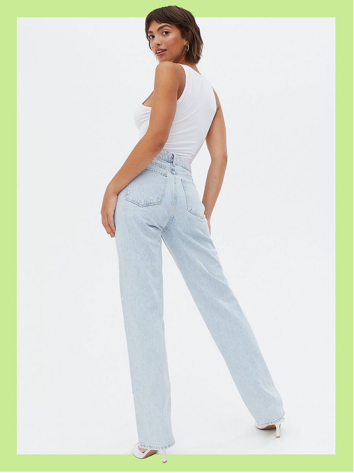 Woman wearing pale blue straight leg jeans, vest top and heels