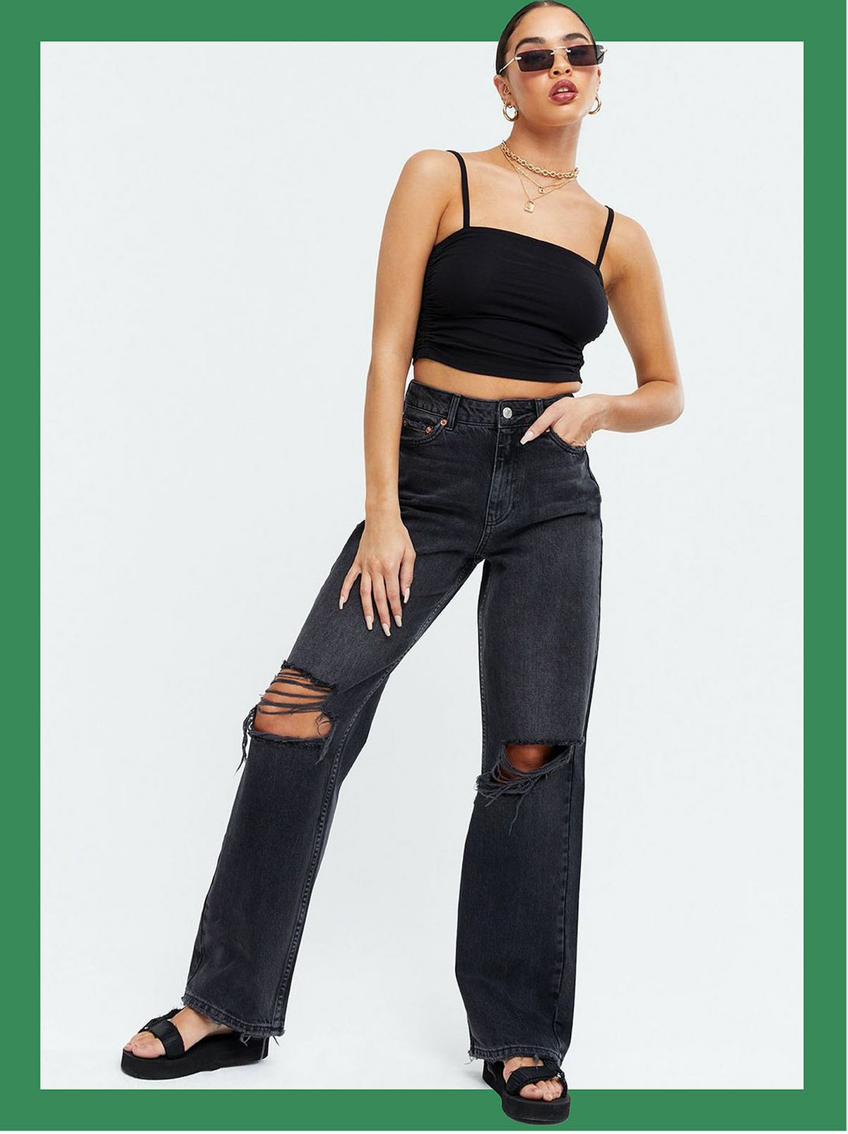Woman wearing black ripped high rise baggy fit jeans, cami top and sandals