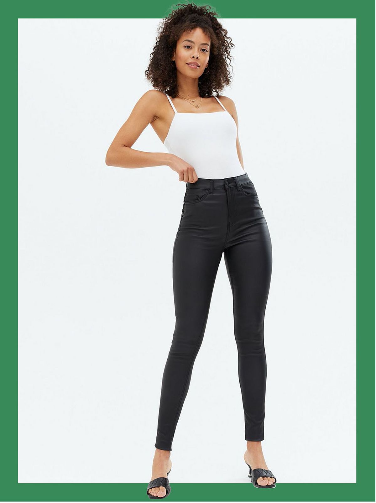 Woman wearing black leather look supper skinny jeans, white top and heels