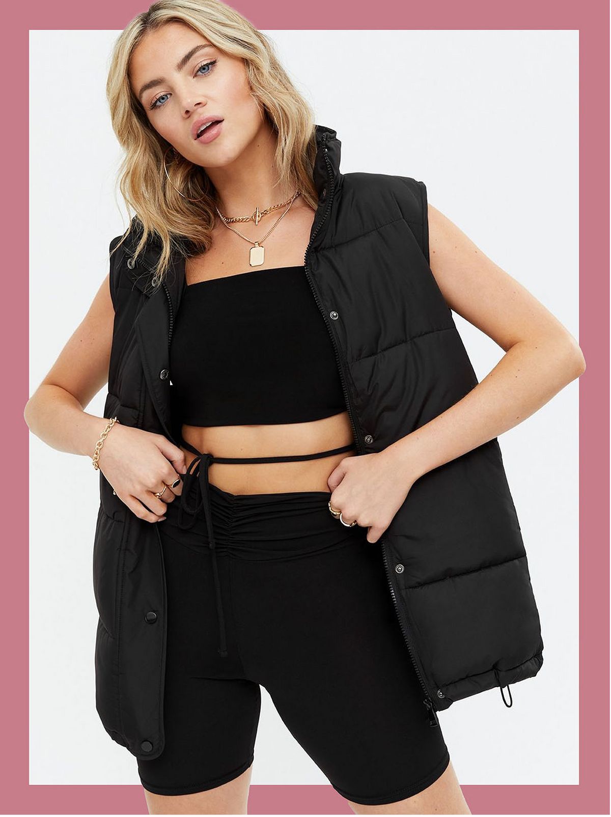 Woman wearing a black high neck padded gilet, crop top and cycling shorts