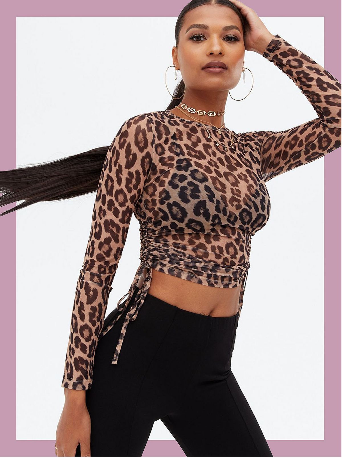 Woman wearing a black leopard print mesh ruched side long sleeve top and trousers