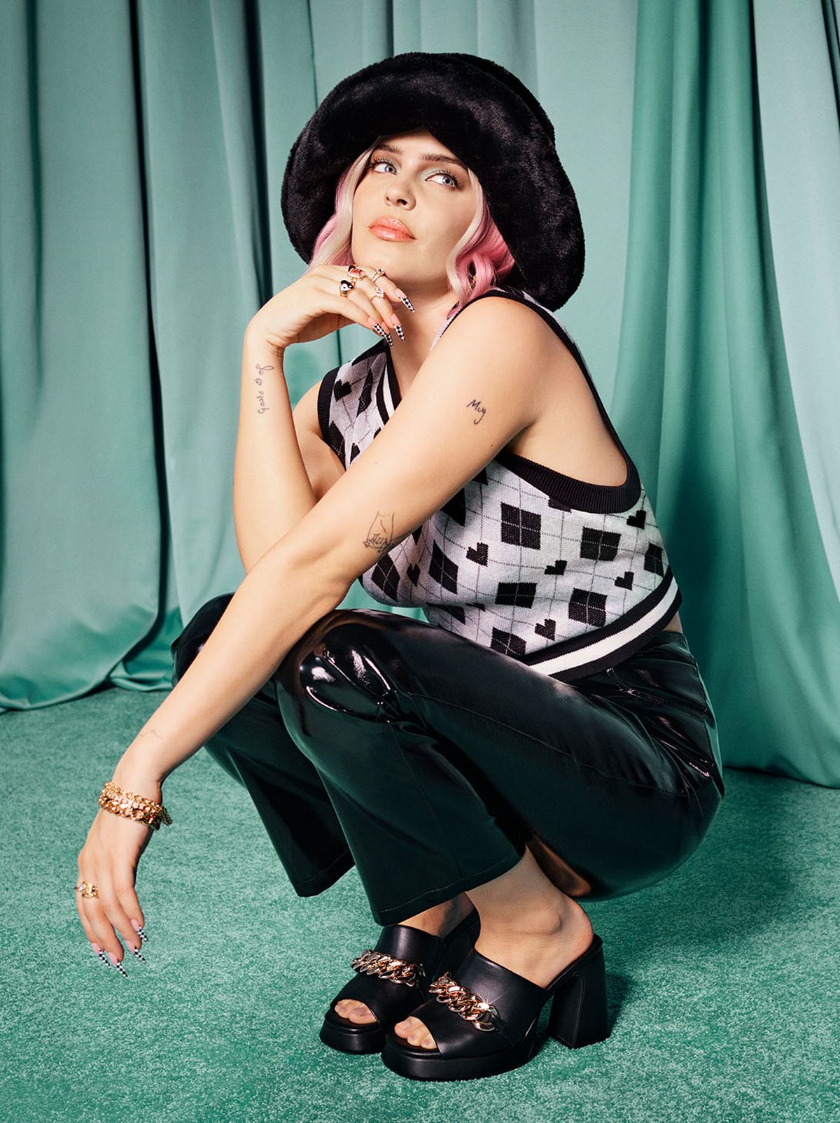 Anne Marie wearing a New Look argyle print vest top, leather look, trousers, heeled sandals and hat	