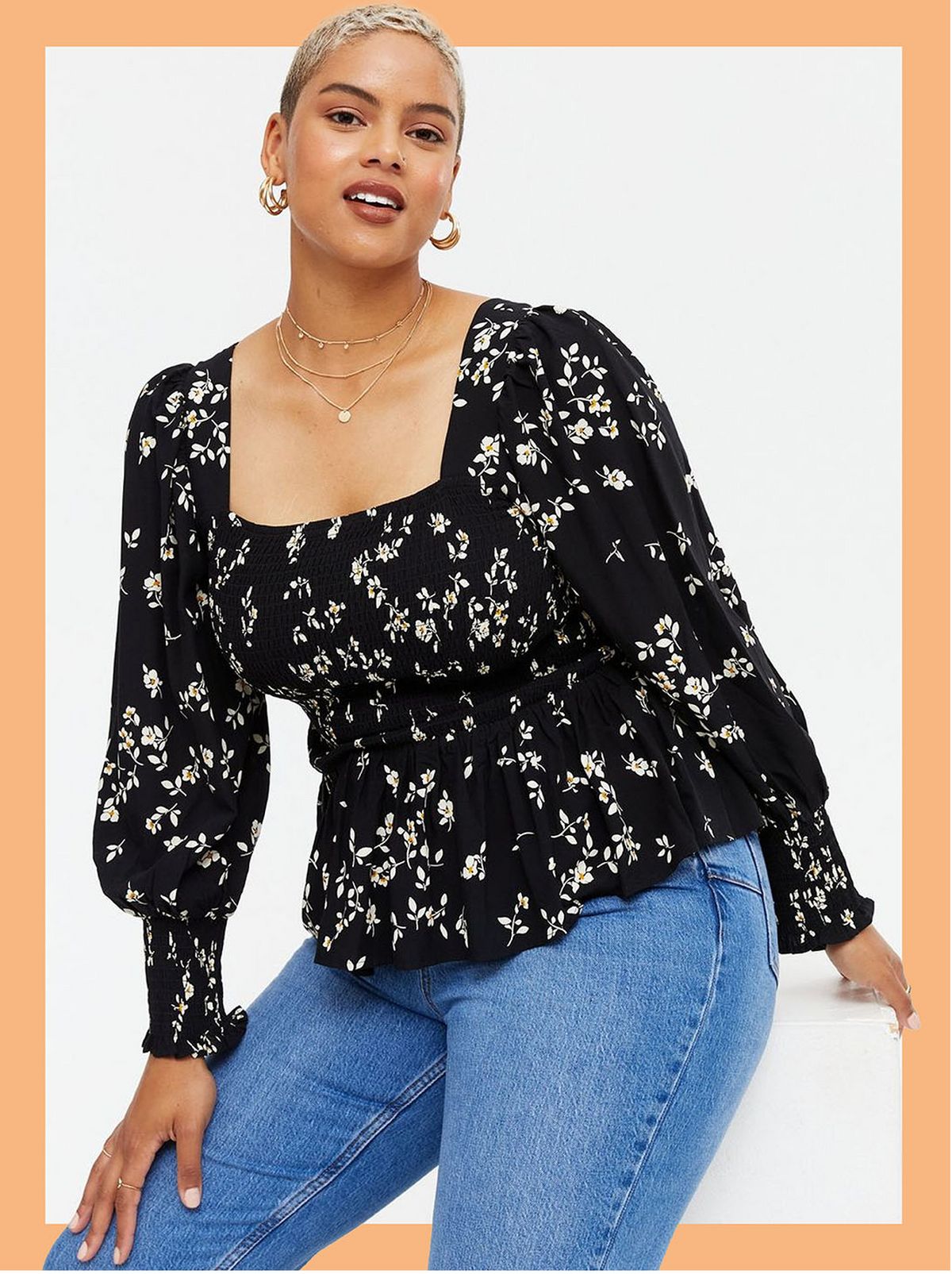 Woman wearing a black floral shirred square neck peplum top and jeans
