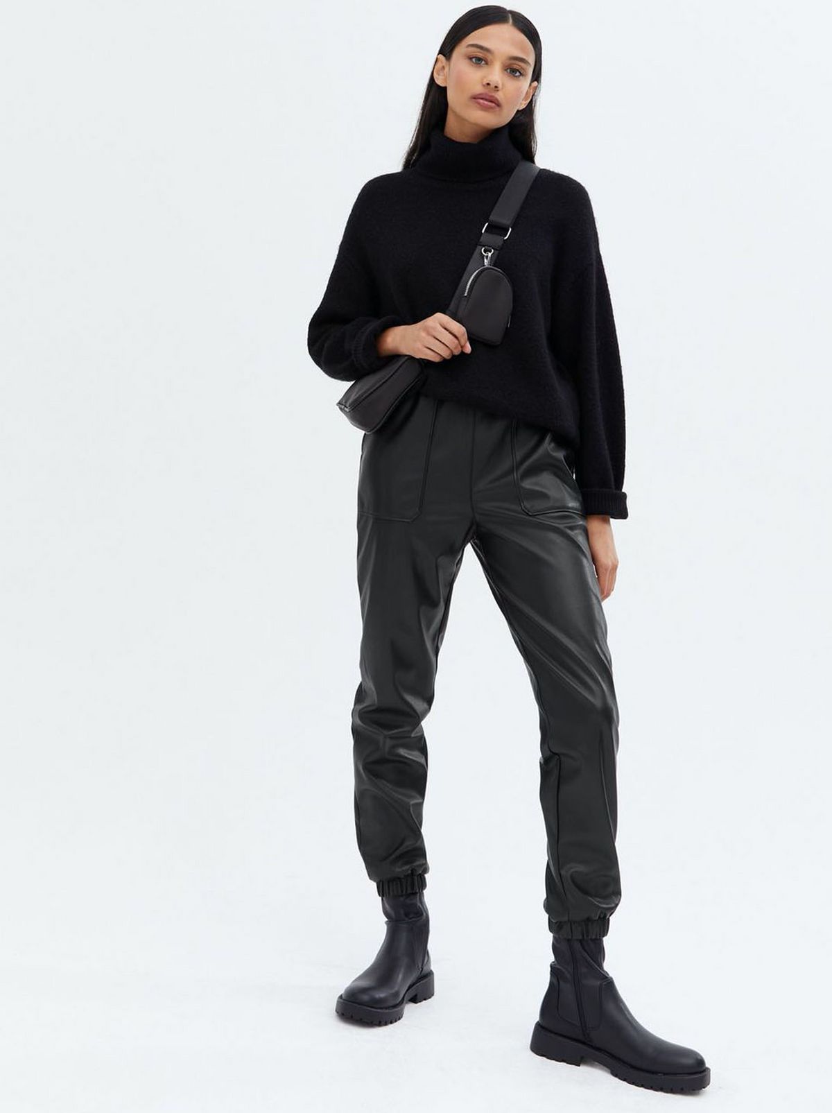 Woman wearing black leather look high waist joggers, black jumper and boots