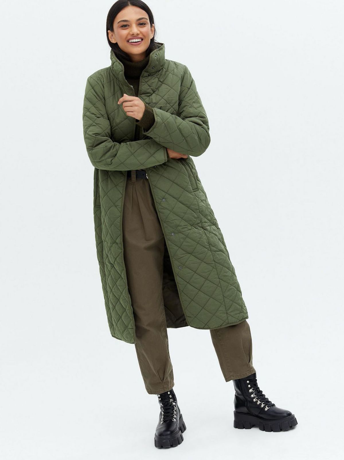 Woman wearing a khaki quilted high neck belted midi coat