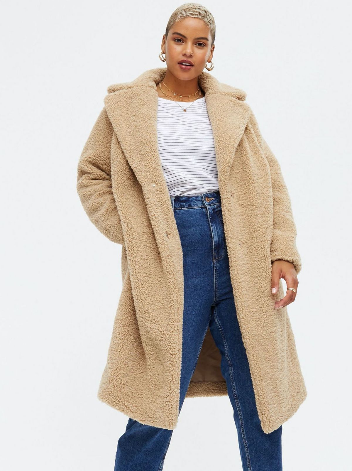 Woman wearing a camel teddy long coat, jeans and striped t-shirt