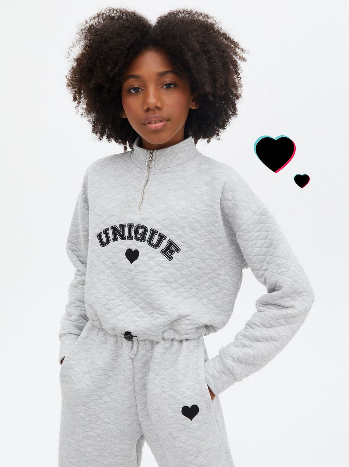 Girl wearing a grey quilted 'Unique' logo sweatshirt and matching joggers	