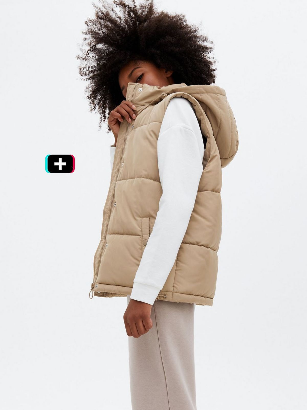 Girl wearing a camel puffer hooded gilet, long sleeve top and trousers	