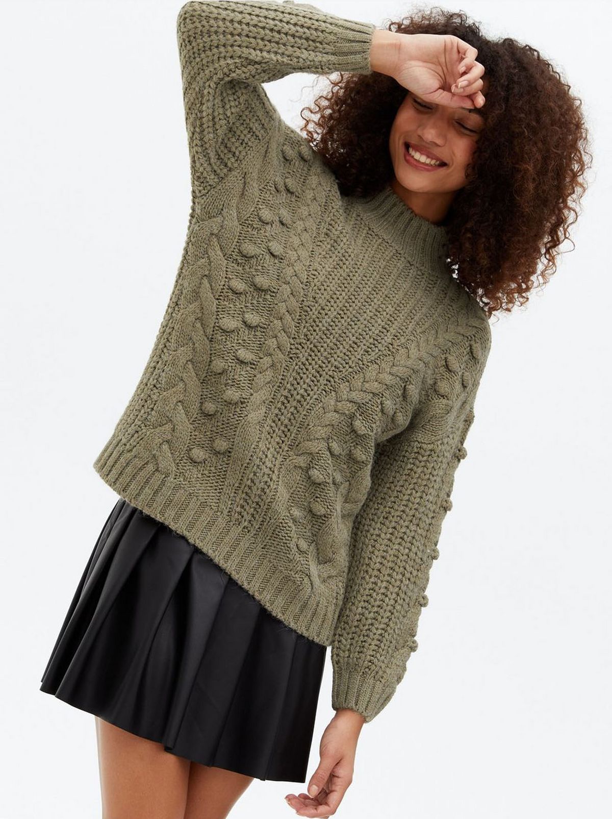 Woman wearing a khaki knit high neck jumper	