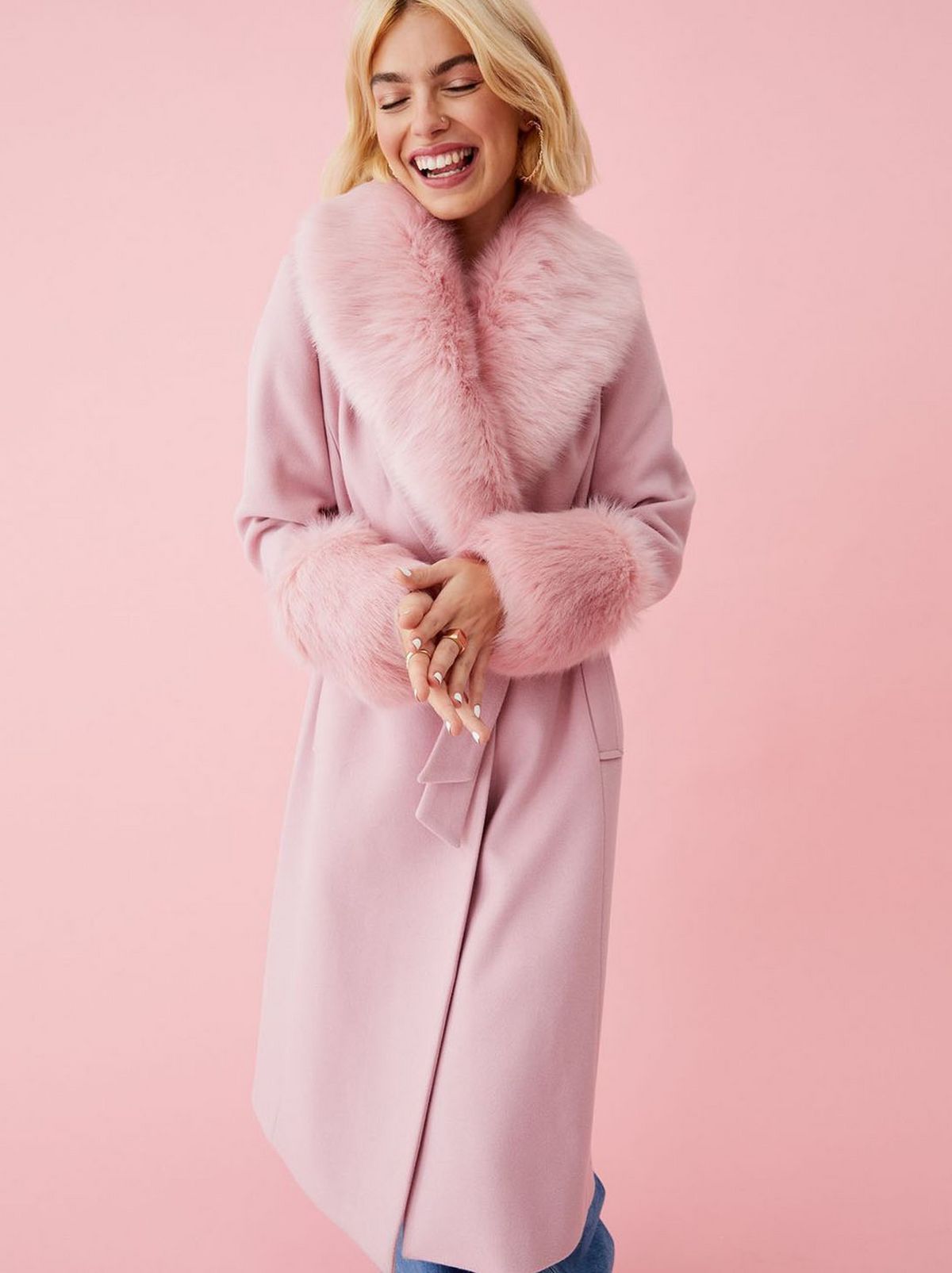 Woman wearing a pale pink faux fur trim coat	