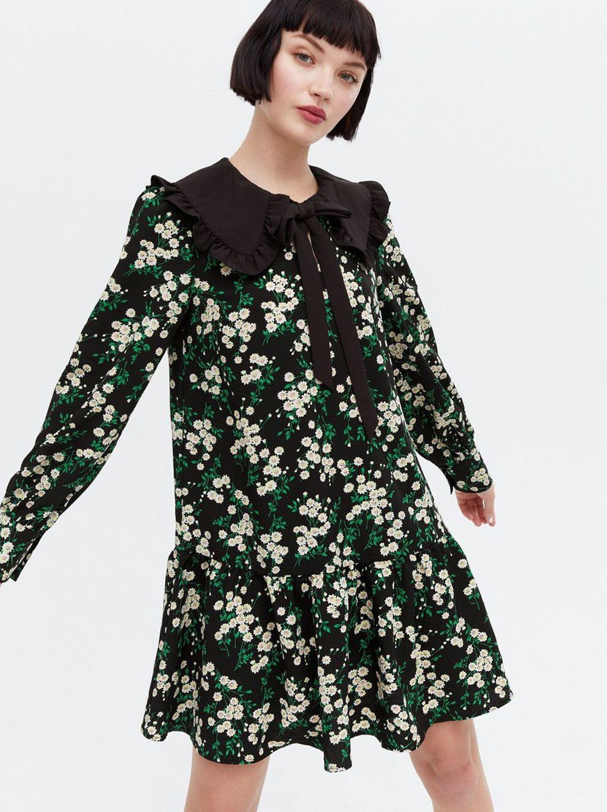 Woman wearing a green floral frill tie collar smock dress