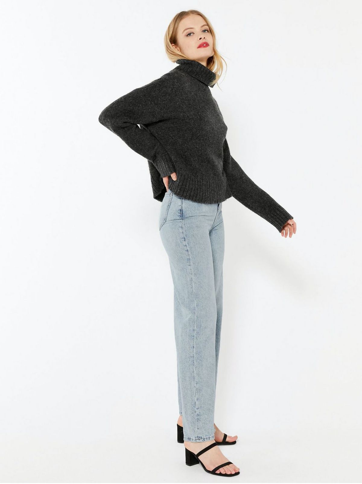 model wears high neck grey jumper and blue wide leg jeans