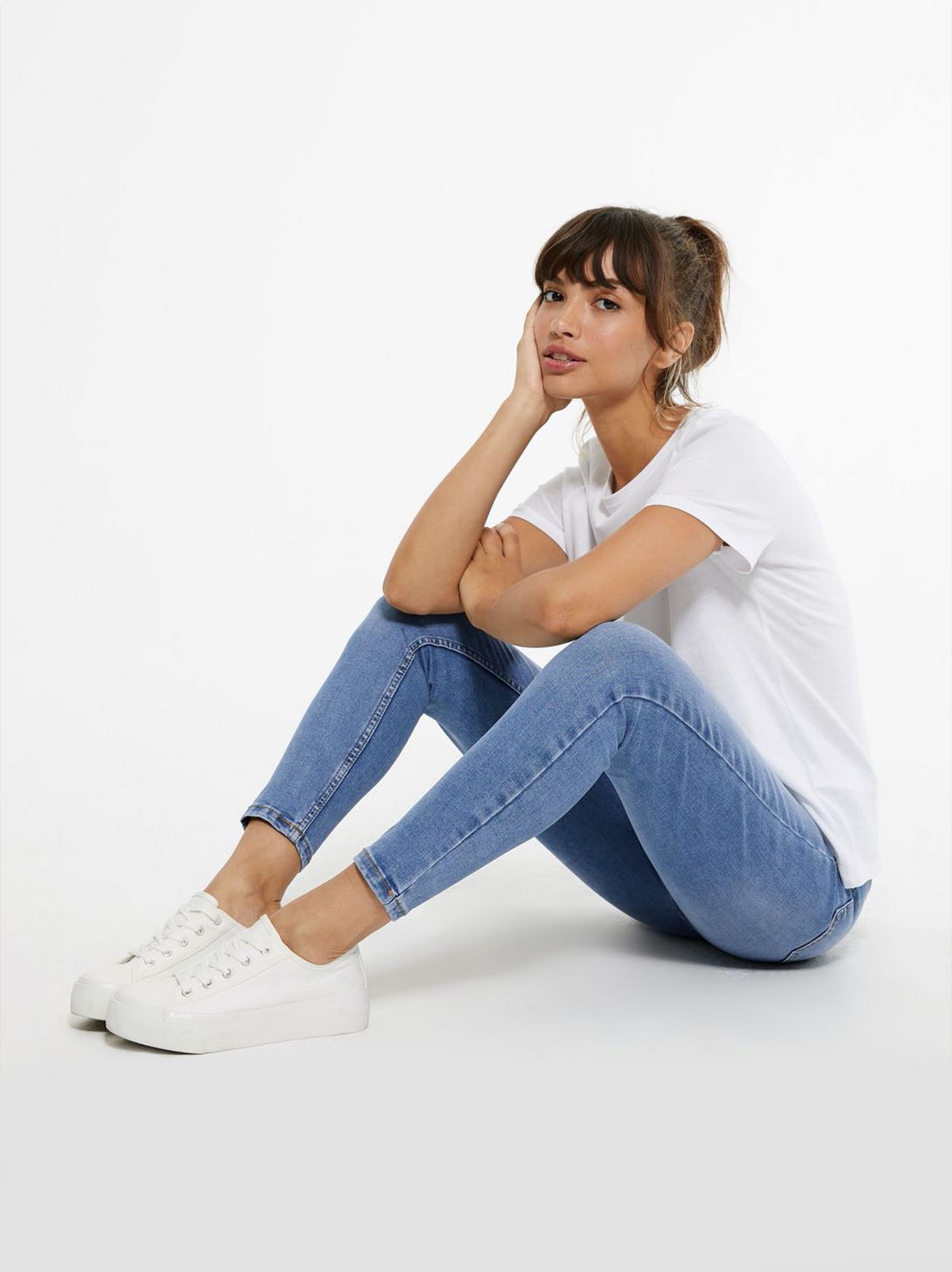 model wears white t-shirt and blue lift and shape skinny jeans
