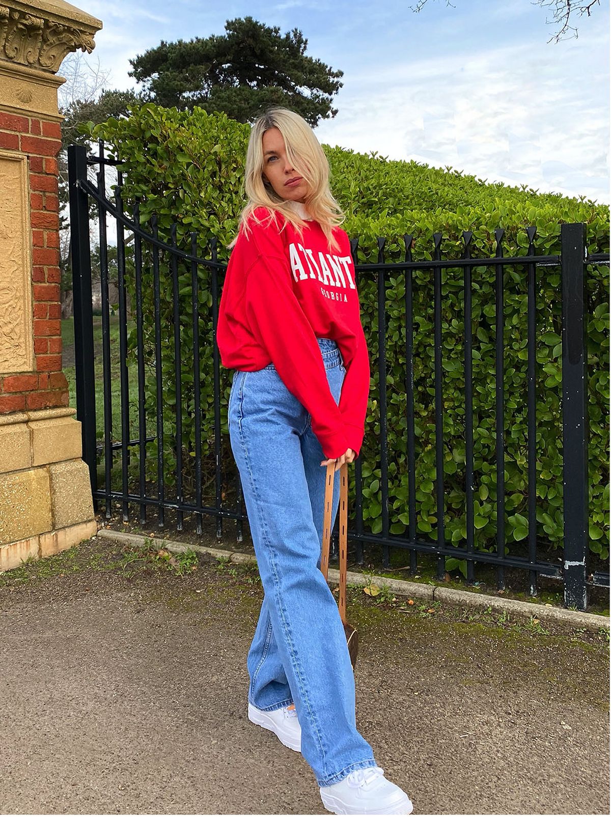 woman wears red sweatshirt and blue wide leg jeans