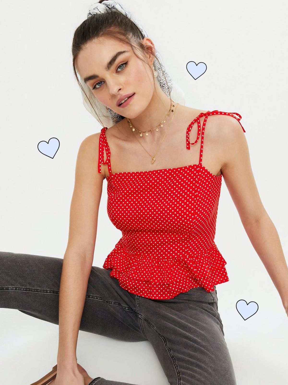 Woman wearing red spot ruffle peplum tie strap cami and dark grey jeans