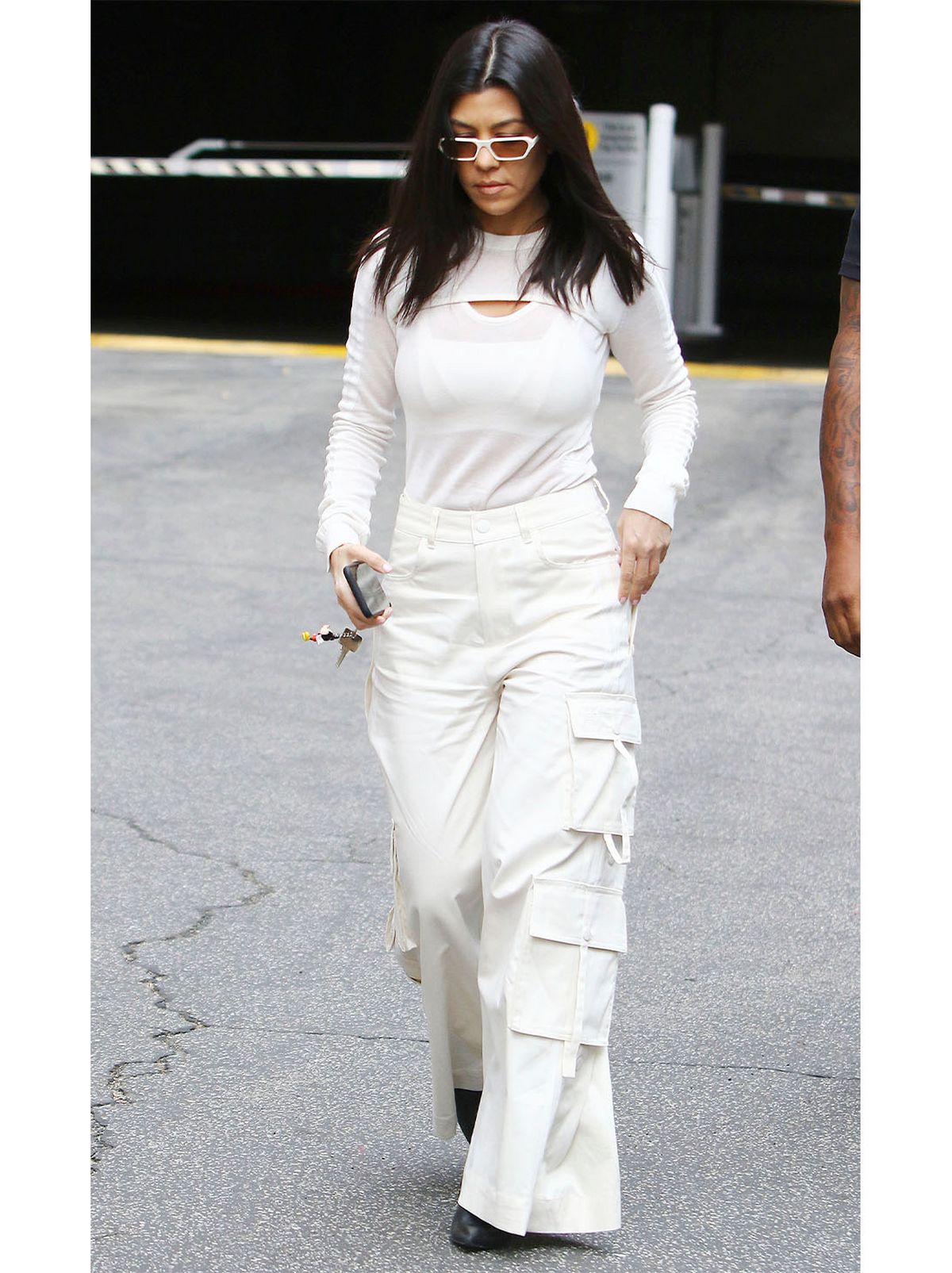 Kourtney Kardashian wearing a white top and white trousers