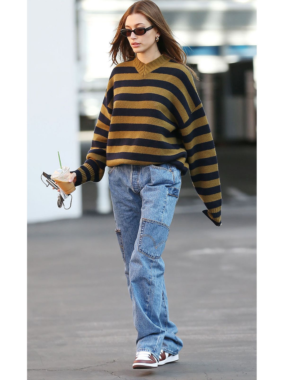 Hailey Bieber wearing a black strip jumper with blue jeans