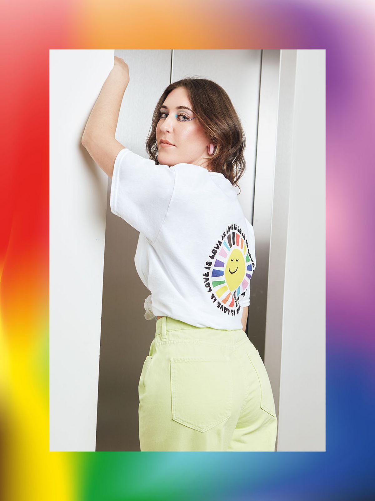 Lauren Tuch is facing away from the camera looking over her shoulder wearing a light green denim skirt and a white T shirt	