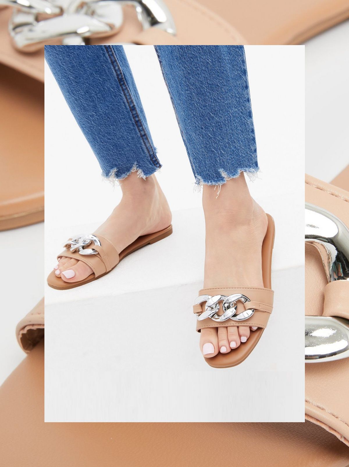 There is a person wearing a pair of flat chain sliders and some blue jeans
