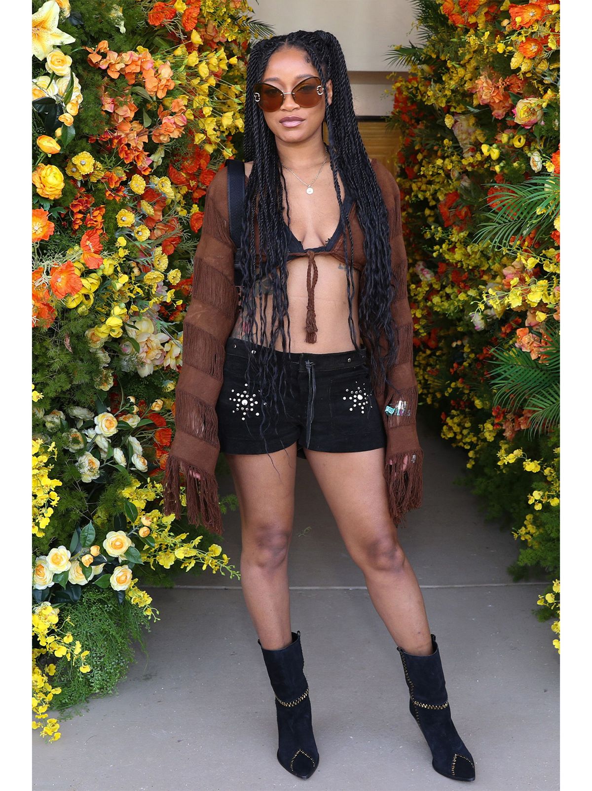 Keke Palmer wears a pair of black cowboy boots and a pair of glittery denim shorts and a brown top