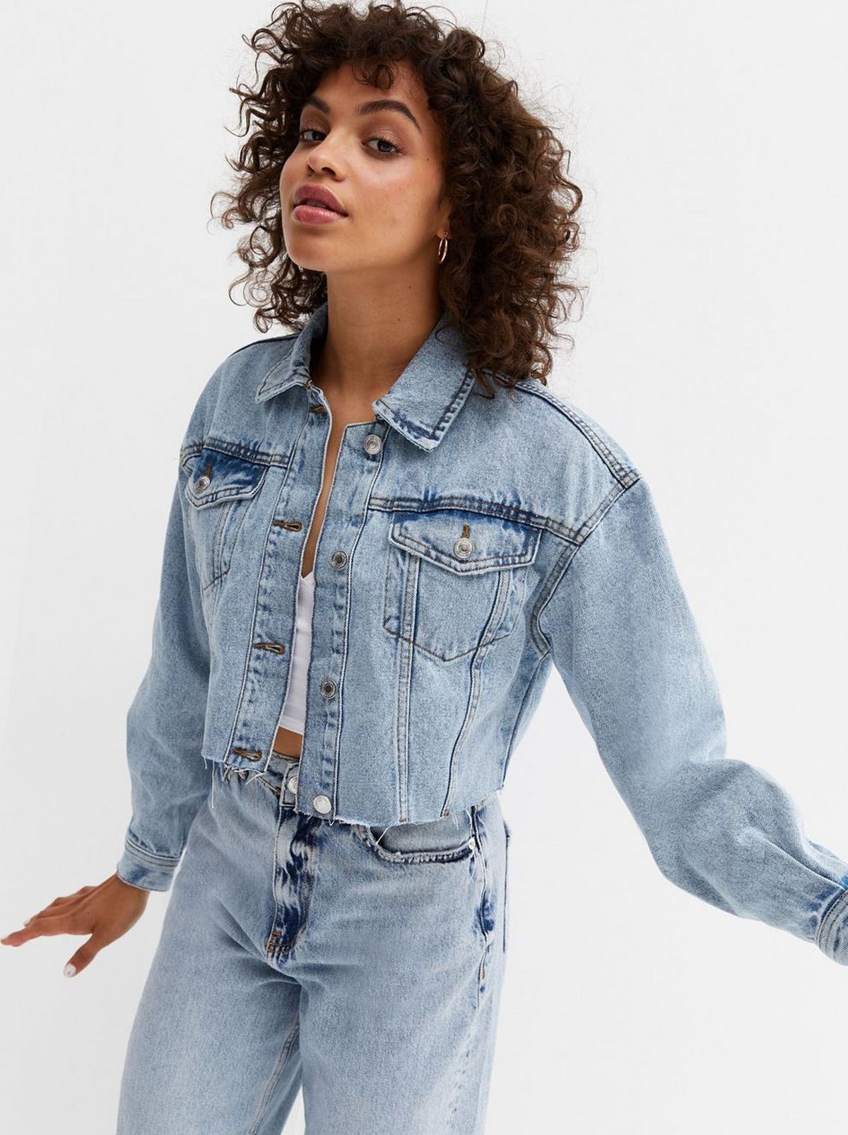 A women stares at the camera wearing a matching faded denim jacket and pair of denim jeans