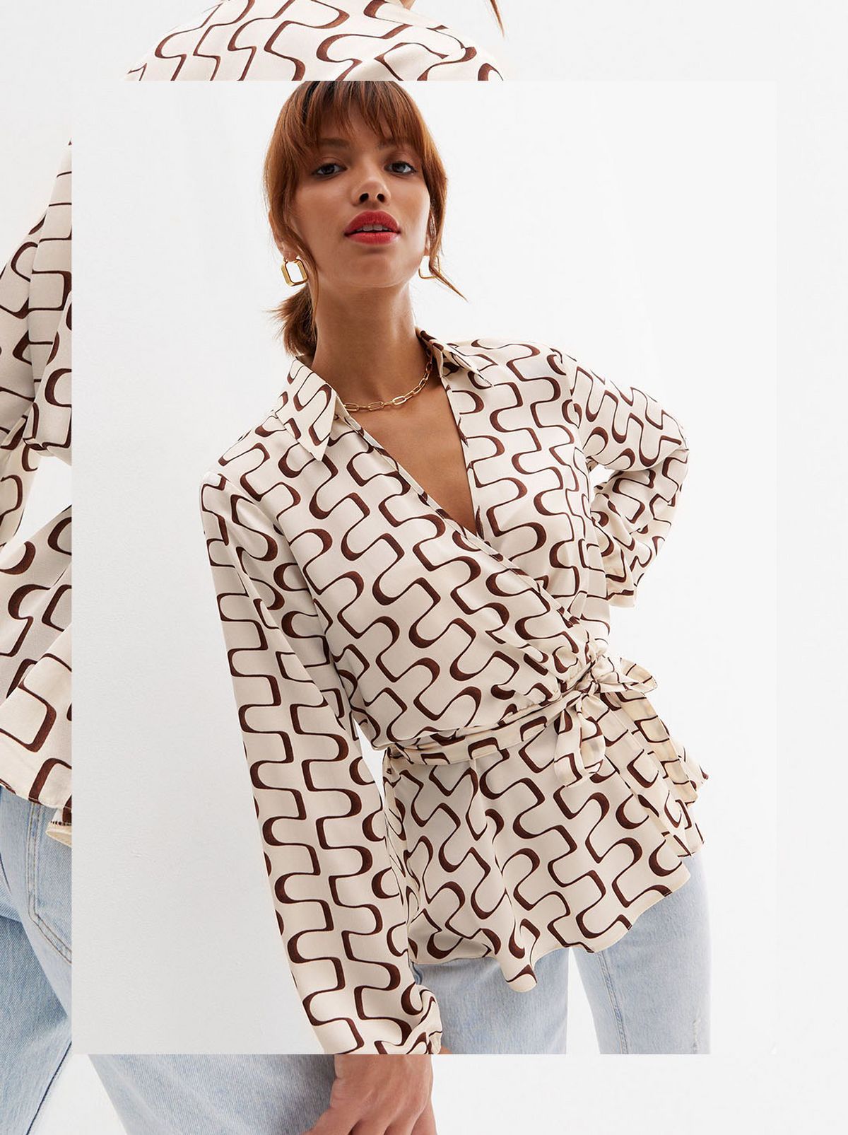 There is a women standing in front of a white background with her head tilted upwards looking at the camera wearing a patterned long sleeve collared top and a pair of washed skinny jeans