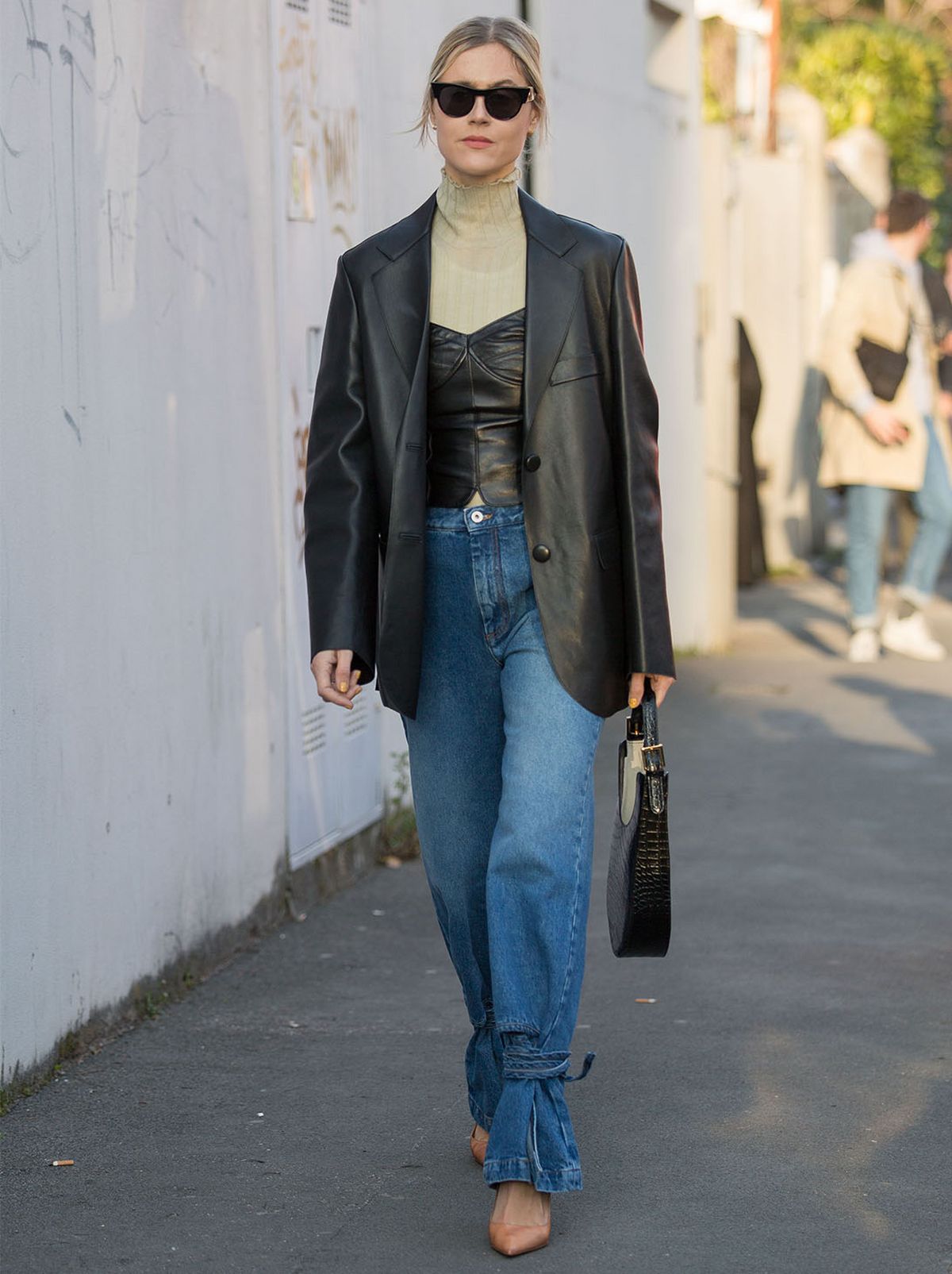 Woman walking, wearing a black leather blazer, jeans and roll neck top