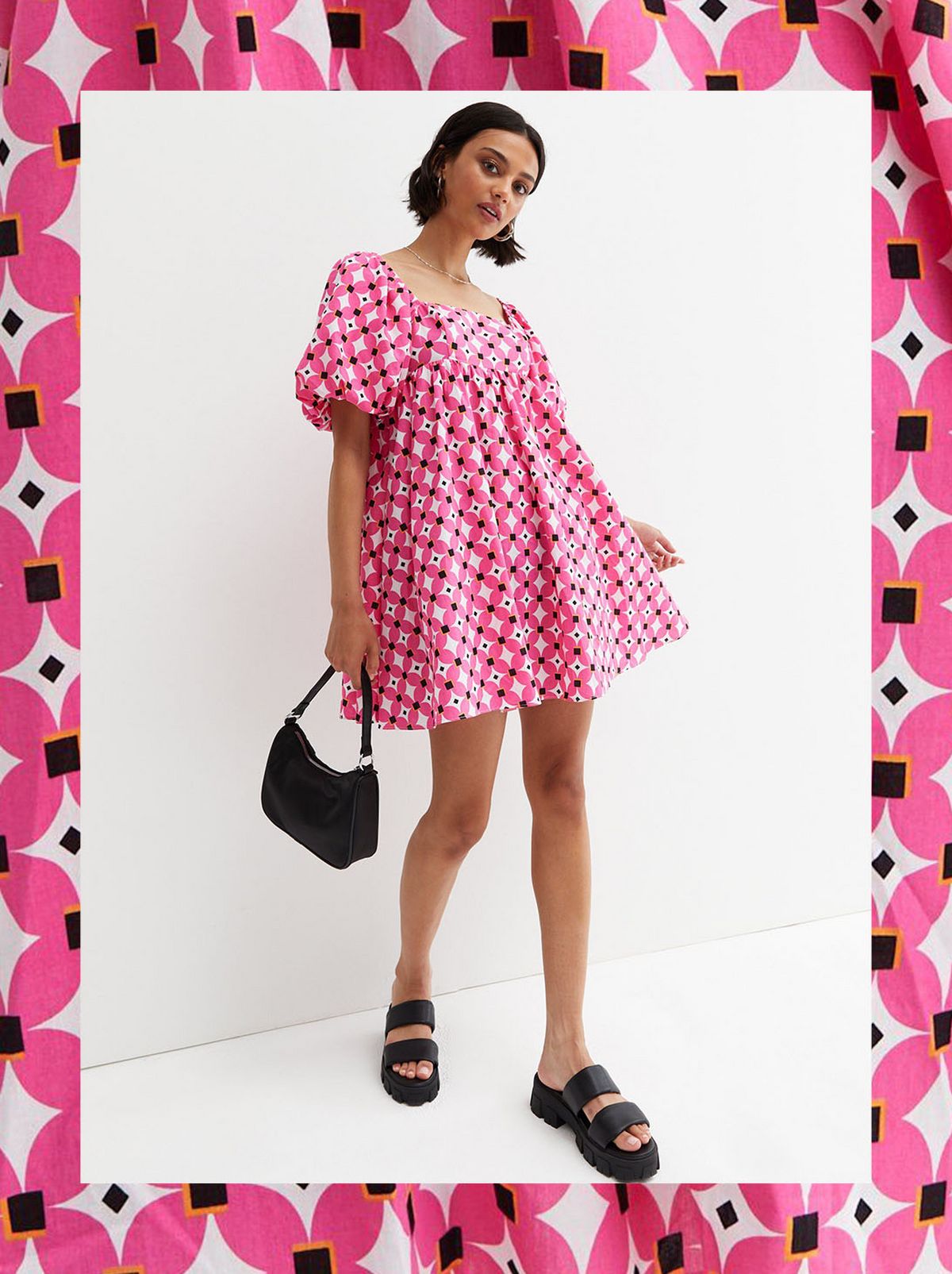 A women slowly walks forwards looking down at the camera, wearing a pink patterned midi dress and wearing black sandals 