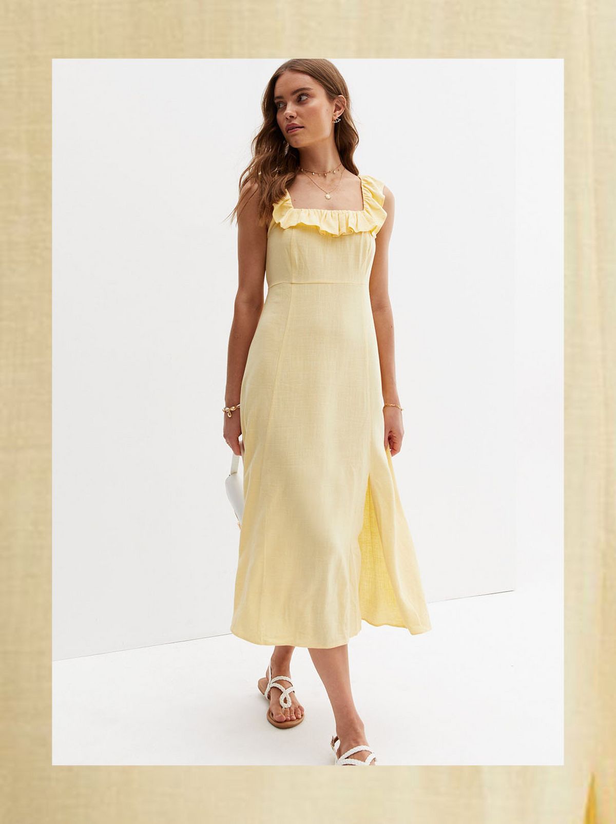 There is a women looking away from the camera, walking forwards while wearing a long yellow dress