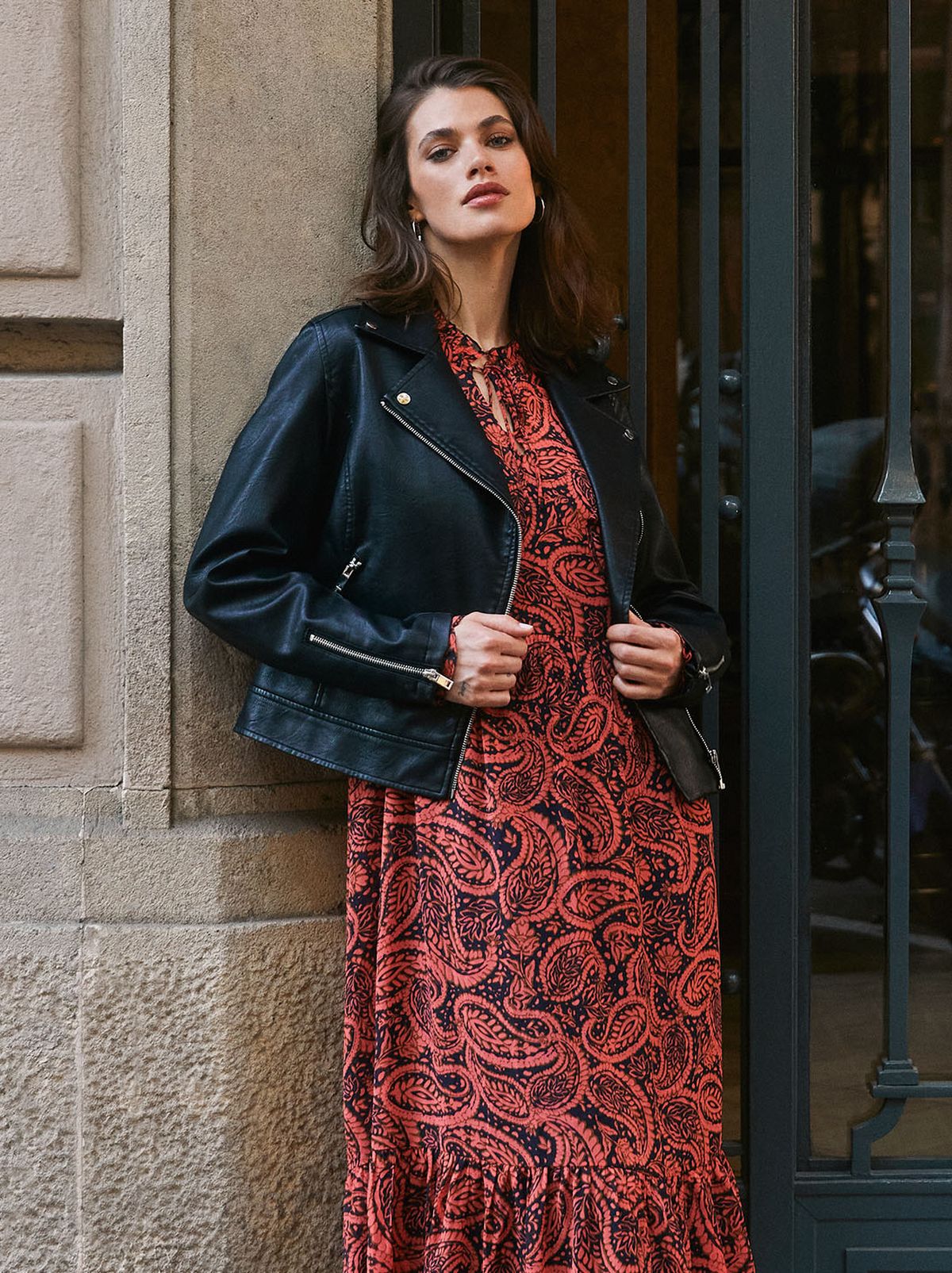 Woman wearing a black leather-jacket and red printed dress	