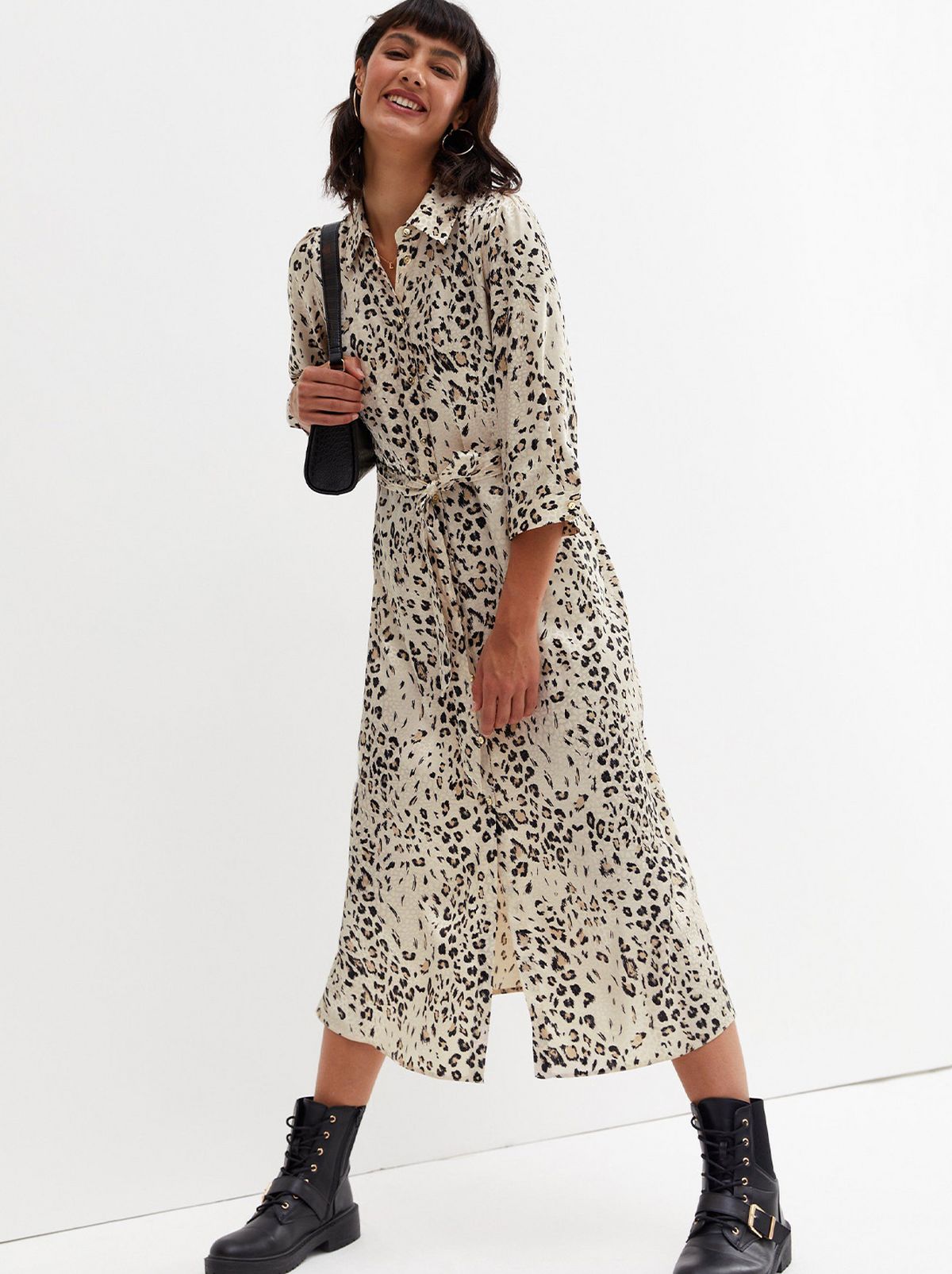 Woman wearing a white leopard print midi shirt dress, boots and holding a handbag