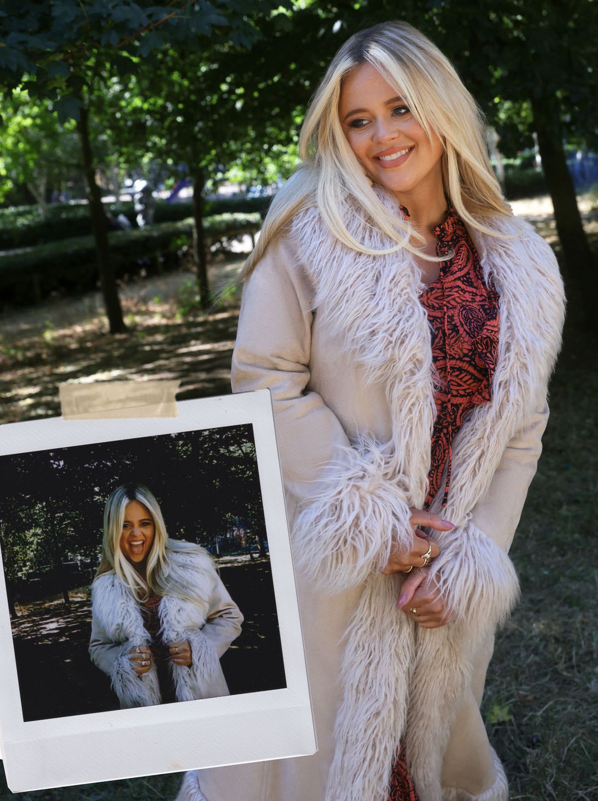 Emily Atack smiles away from the camera, standing in a park wearing a white fur lined coat
