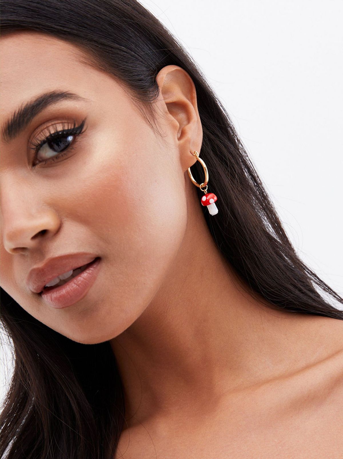 Woman wearing mushroom charm hoop earrings