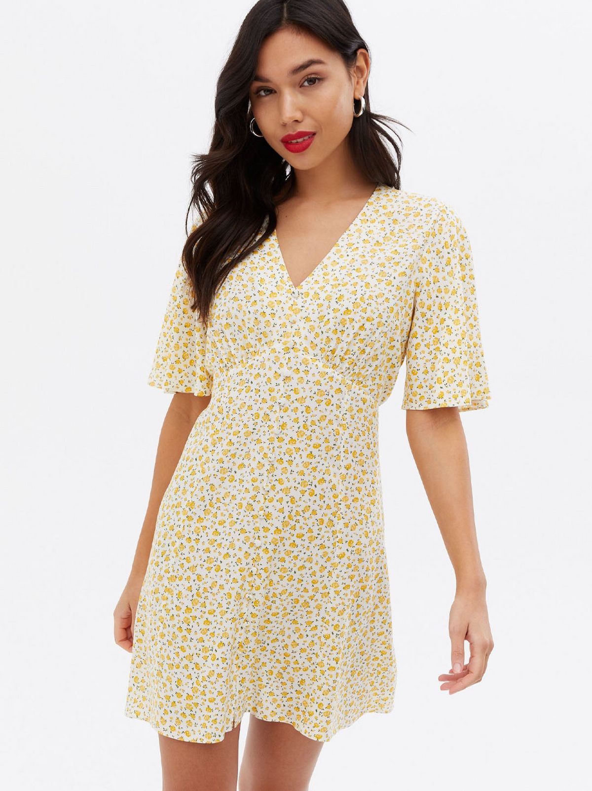 Woman wearing a mustard floral button front mini dress