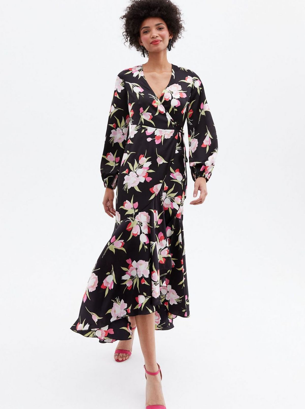 Woman wearing a black floral satin dip hem midi wrap dress