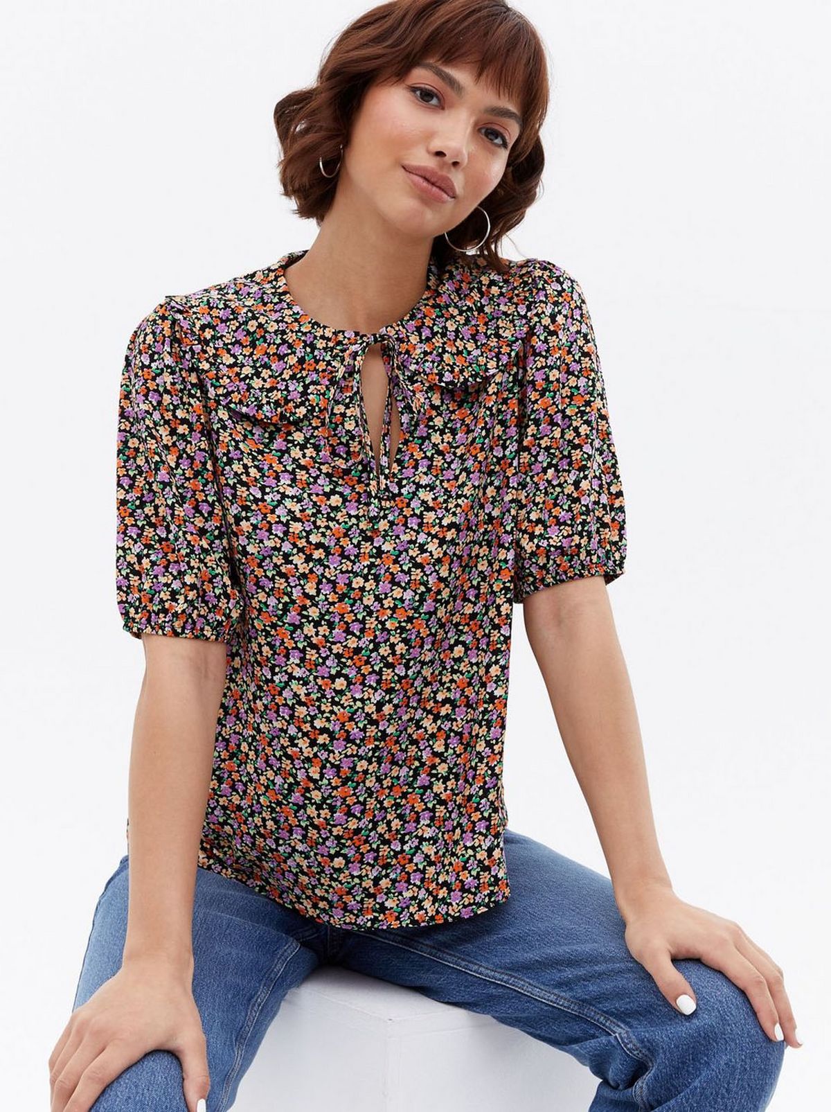 Woman wearing a black ditsy floral tie collared blouse