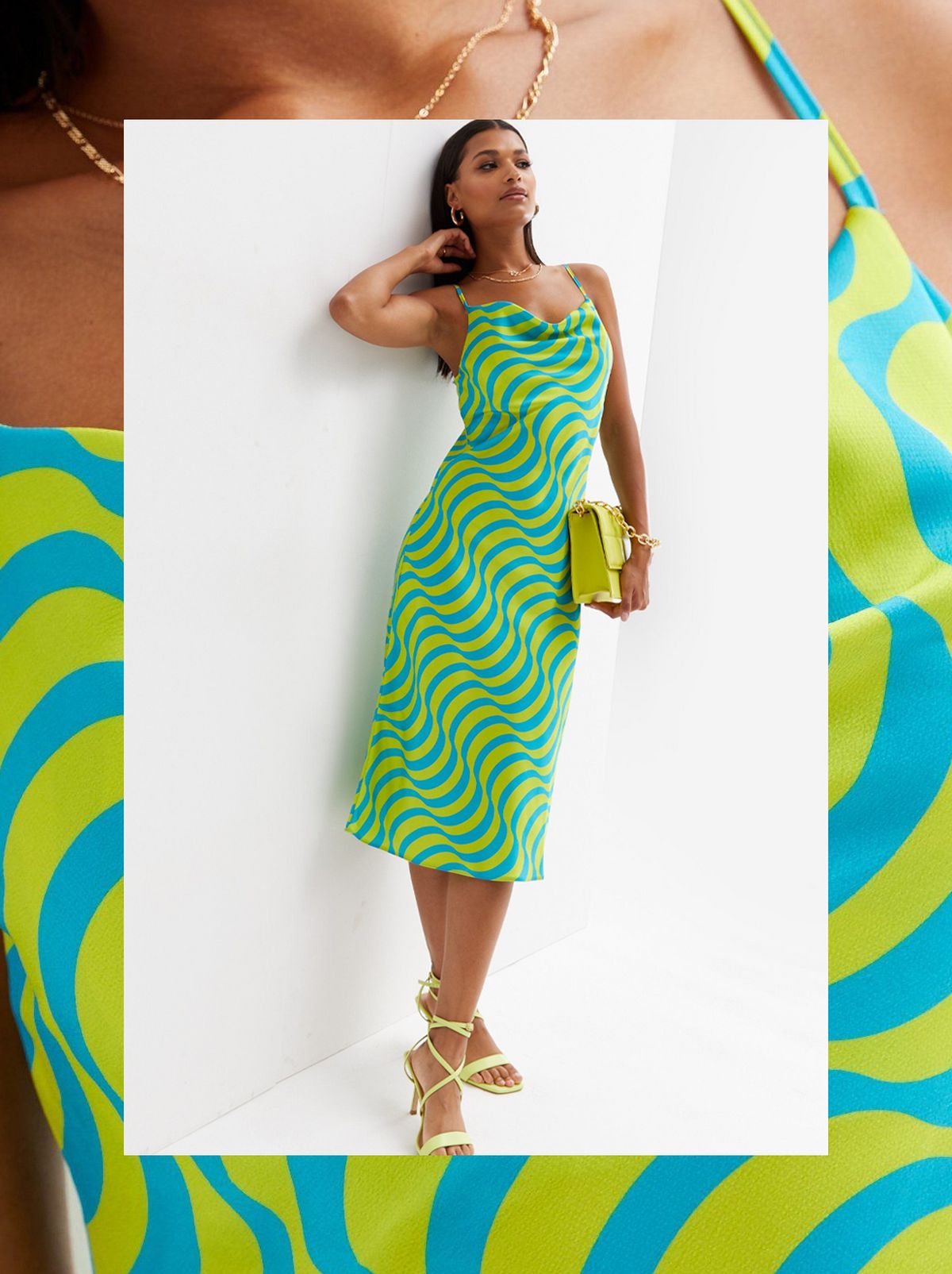 A women leans on a wall wearing a green patterned midi slip dress and holding a lime green bag