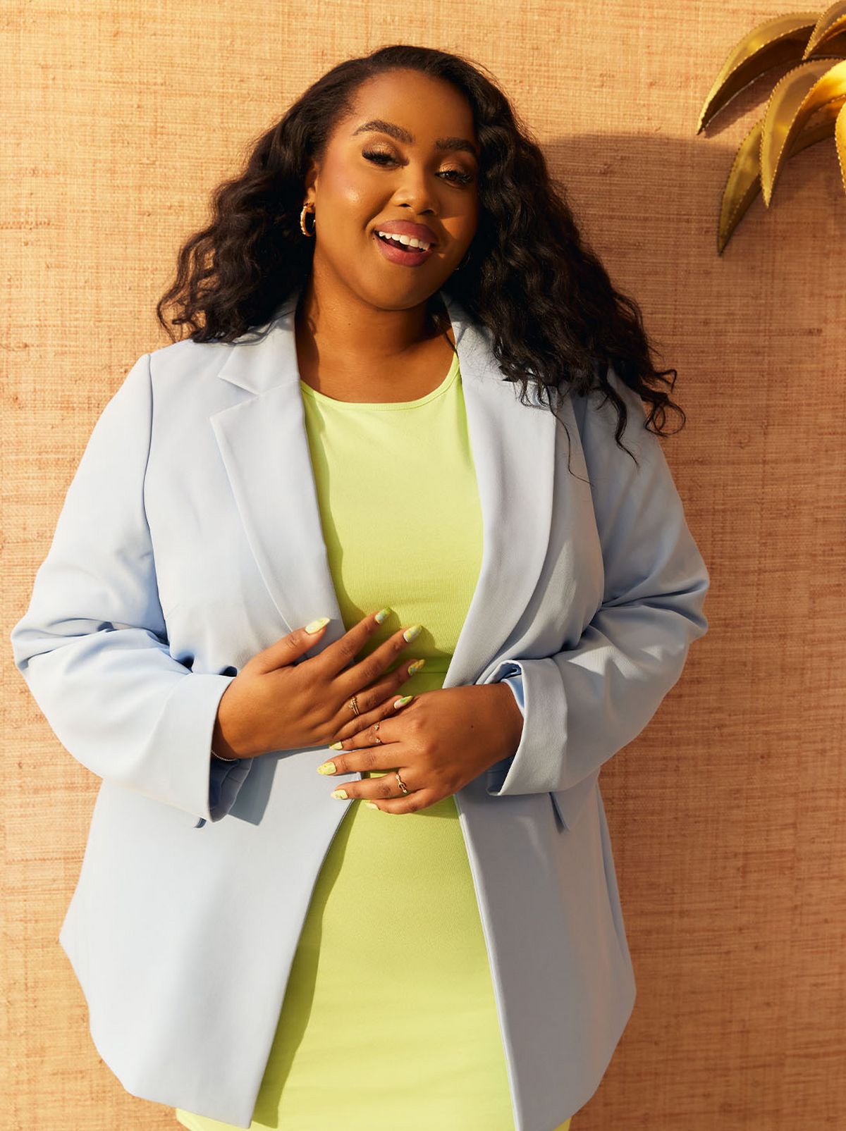 Lauren Nicole is smiling at the camera wearing a pale blue blazer and a lime green mini dress
