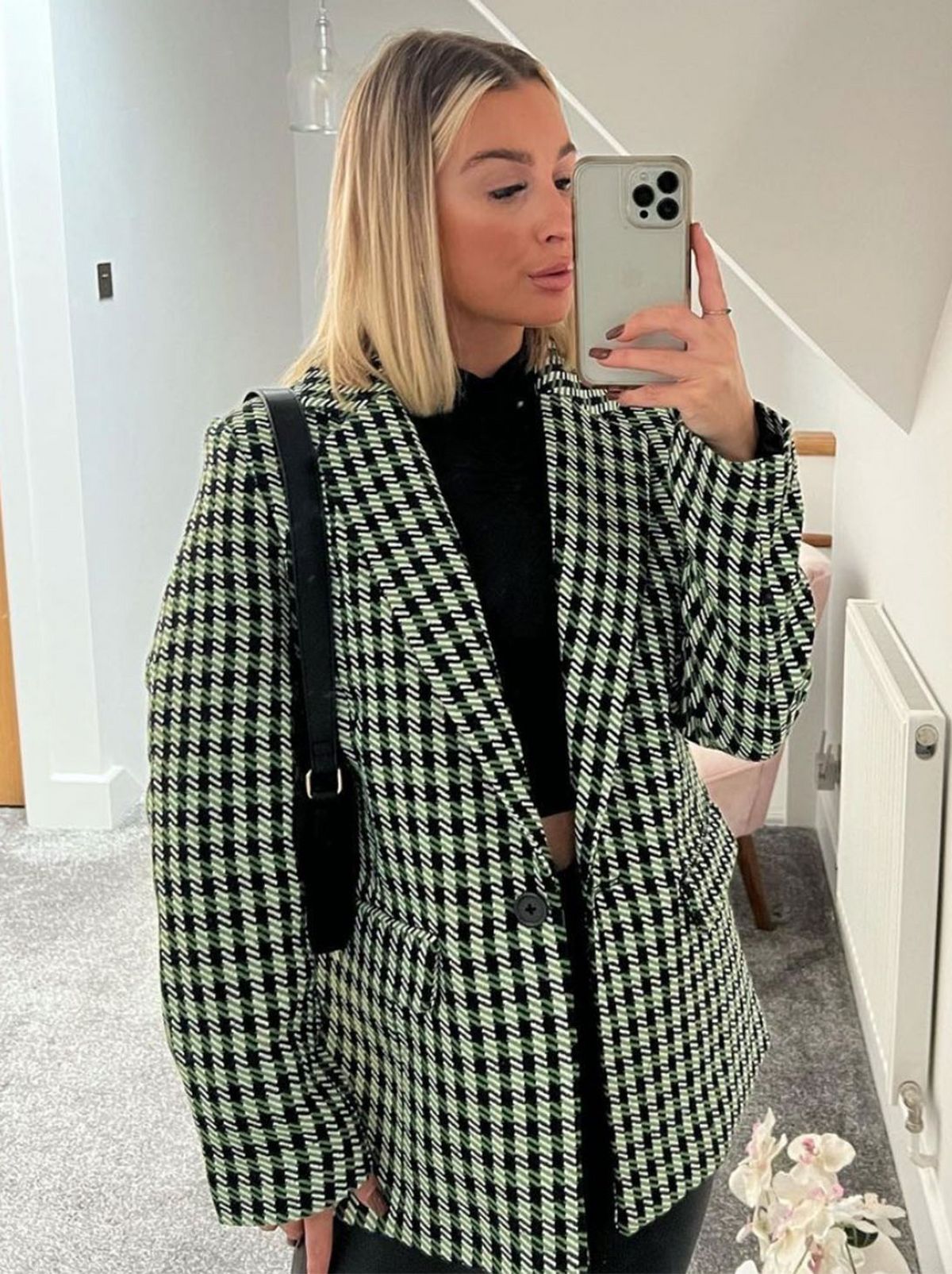 New Looker Georgia is taking a selfie in a room while wearing a black and white checkered blazer with a black top underneath	