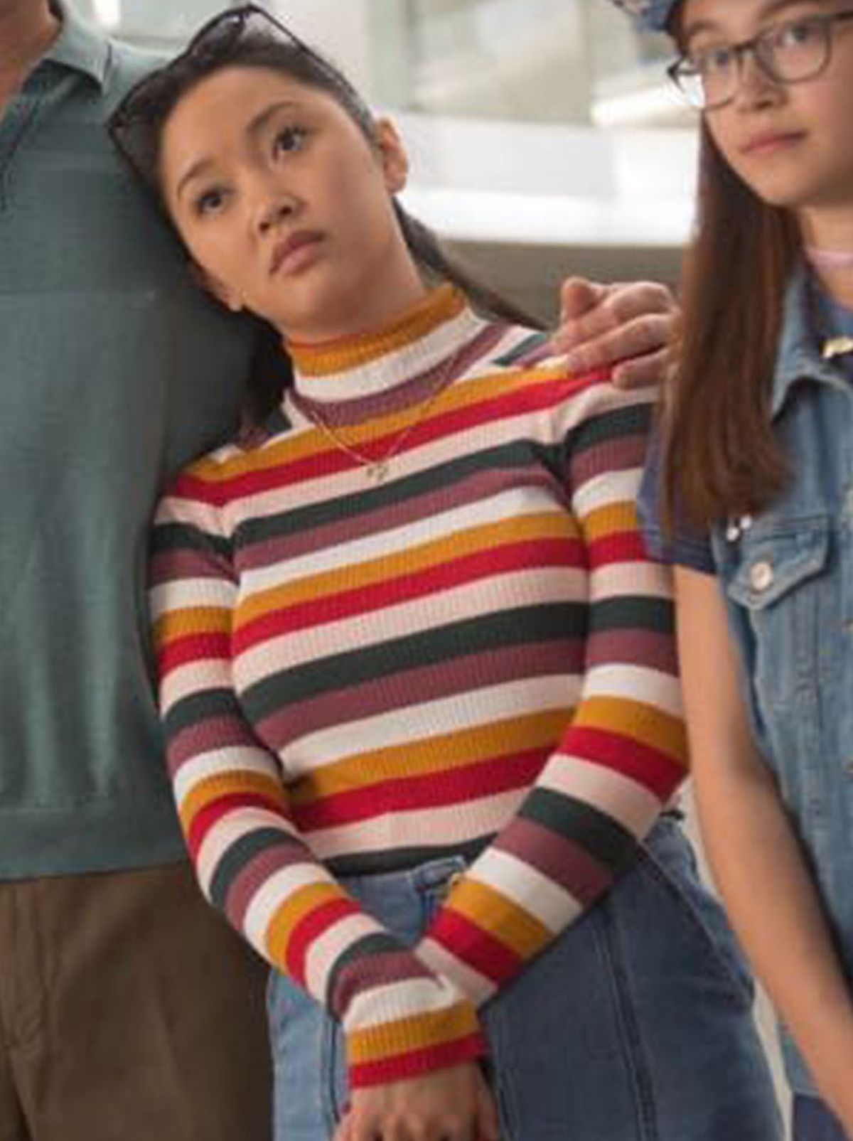 An actor leans on the person next to her that has their arm squeezing their shoulder, they are wearing a bright striped jumper
