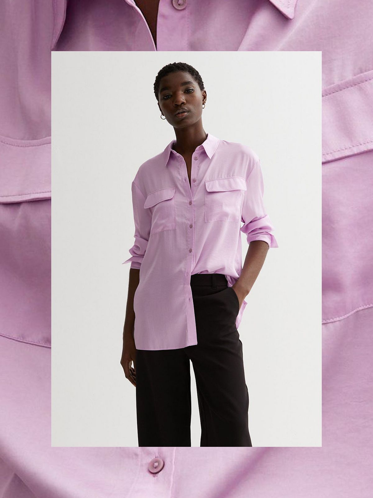 A model sits in a white chair in front of a white background while looking away from the camera & wearing a lilac satin long sleeve shirt	