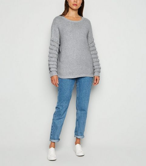 Hellgrauer Pullover mit Bommelärmeln