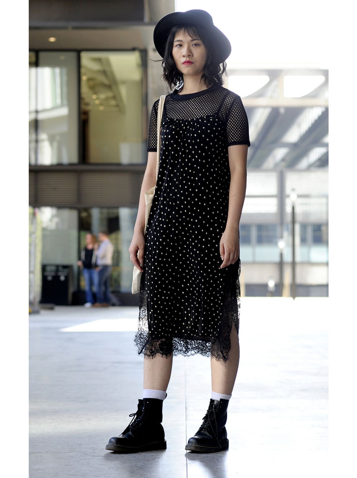 Woman wearing a black midi slip dress styled with black chunky boots and a fedora