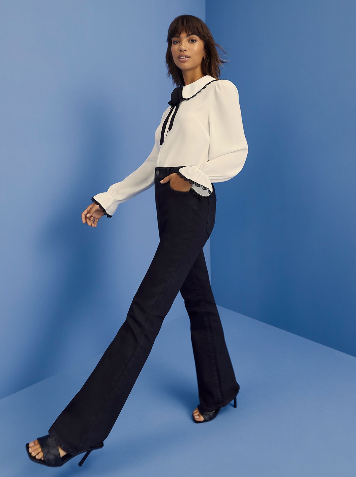 Woman wearing black flare jeans, heels and a white tie front shirt
