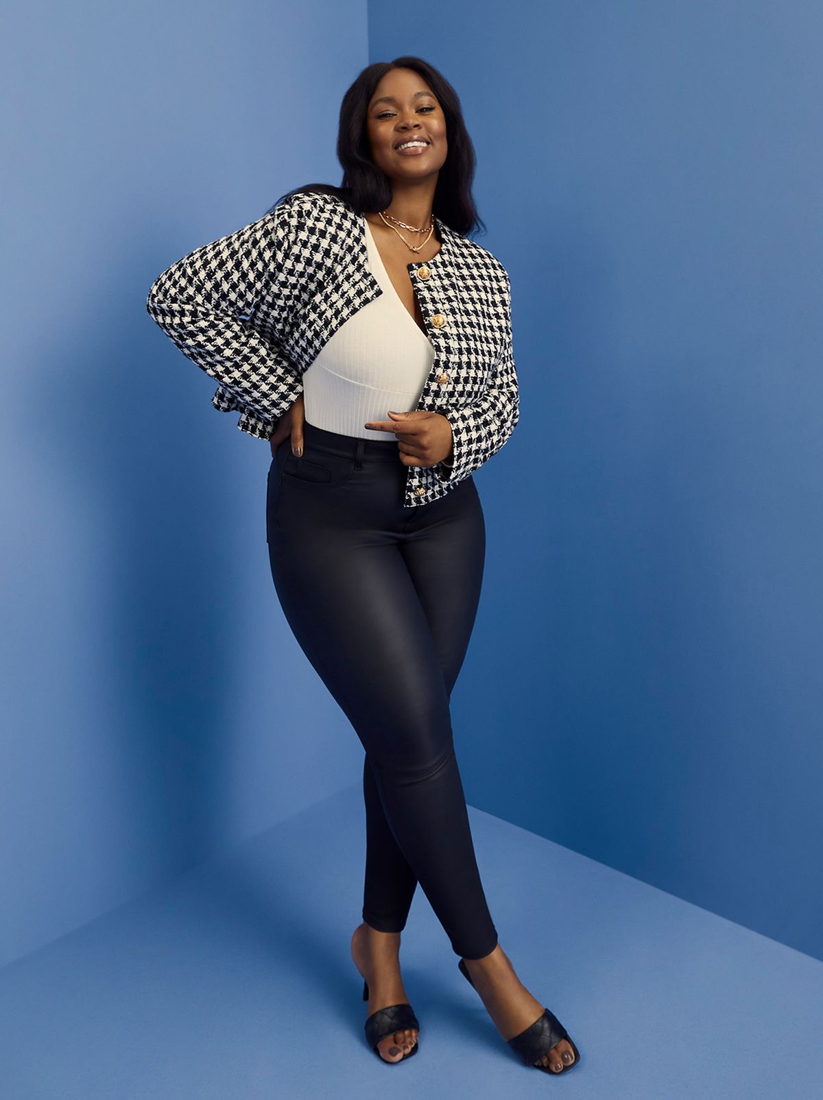 Woman wearing black super stretch skinny jeans, white top, checked blazer and black heels