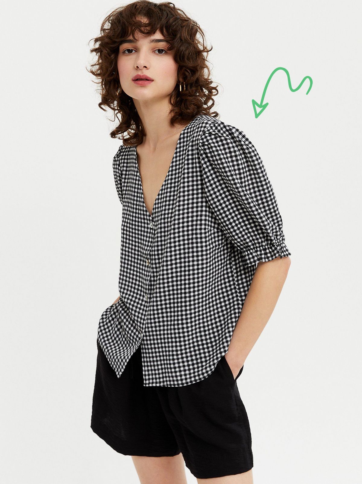 Woman wearing a Black Gingham Puff Sleeve Button Up Blouse and black shorts