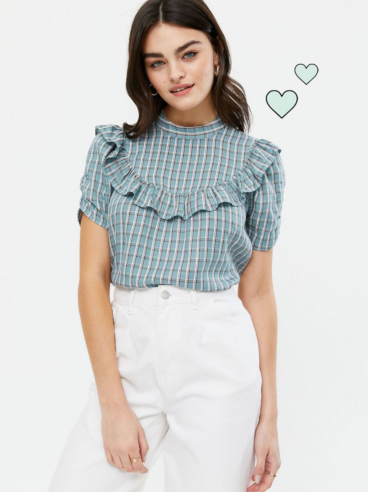 Woman wearing a blue check high neck blouse and white trousers