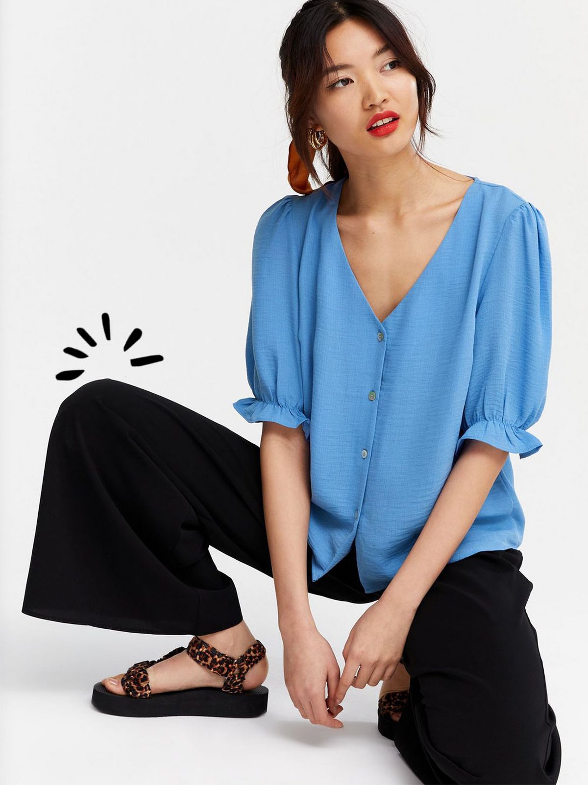 Woman wearing a blue v neck puff sleeve blouse, black wide leg trousers and sandals