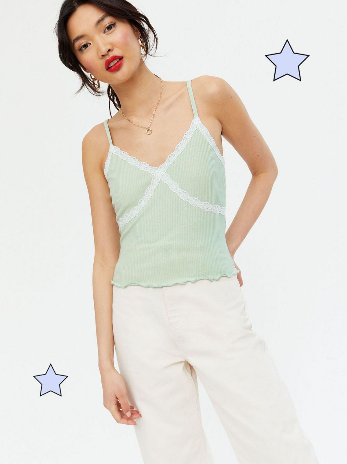 Woman wearing a light green cami top and off white trousers