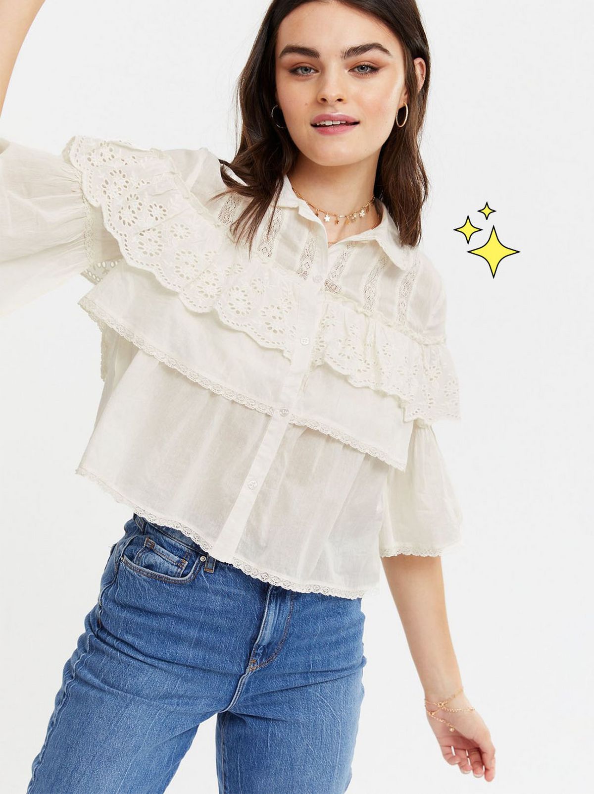 Woman wearing an off white broderie frill shirt and blue jeans